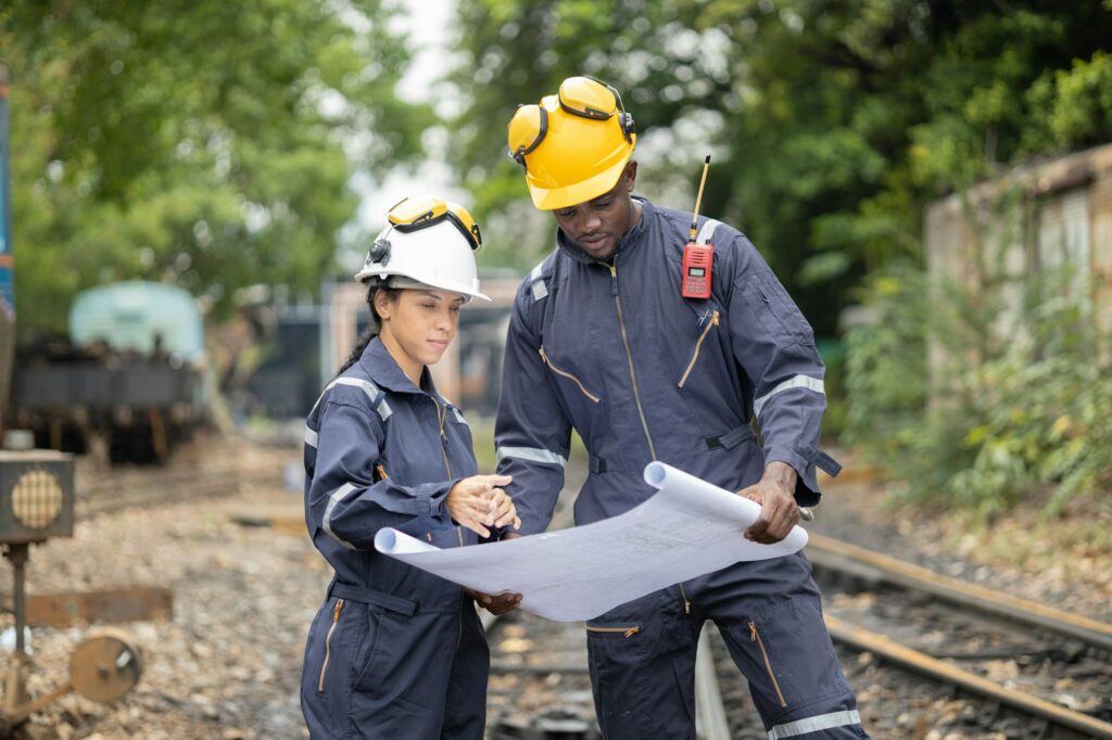 Railway Workers Discussing Plans on Railroad Track